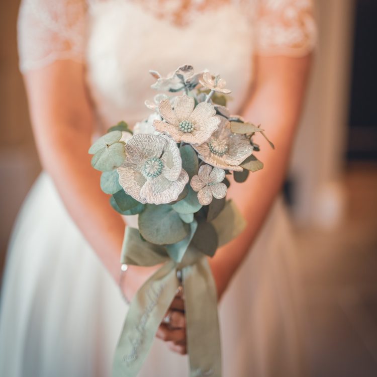 Hannah Mansfield, Goldwork Wedding Bouquet, 2022. 35cm x 15cm (13 ¾” x 6”). Goldwork and monogramming. Silver plated goldwork wires, beads, metallic paint, silver leaf, silk organza, silk ribbon, wire, tissue paper, linen ribbon, stranded embroidery thread. Photo: Sam Lucas